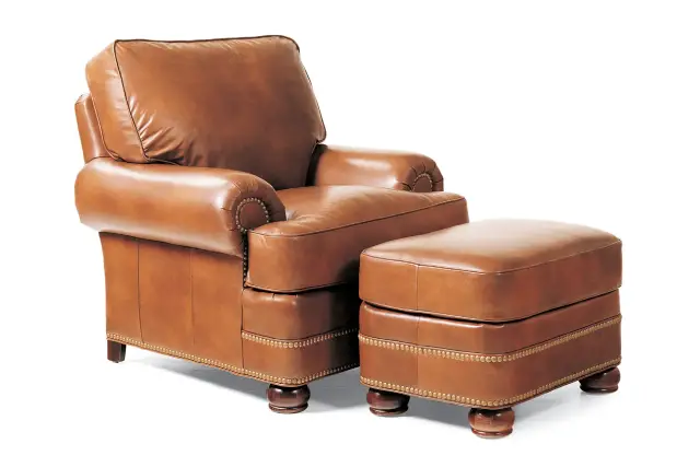 Brown leather armchair with matching ottoman and brass stud detailing.